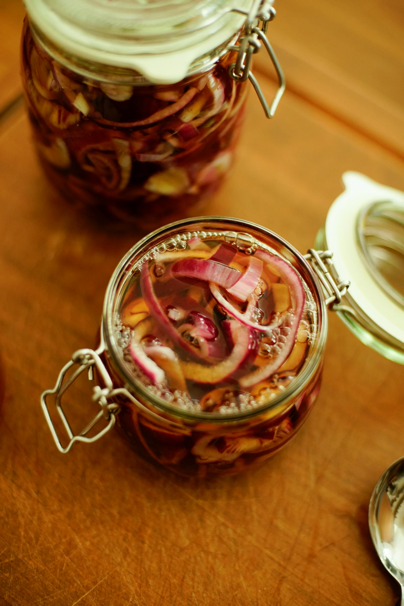 Top-down view of homemade pickled onions in jars, showcasing rich colors and textures.