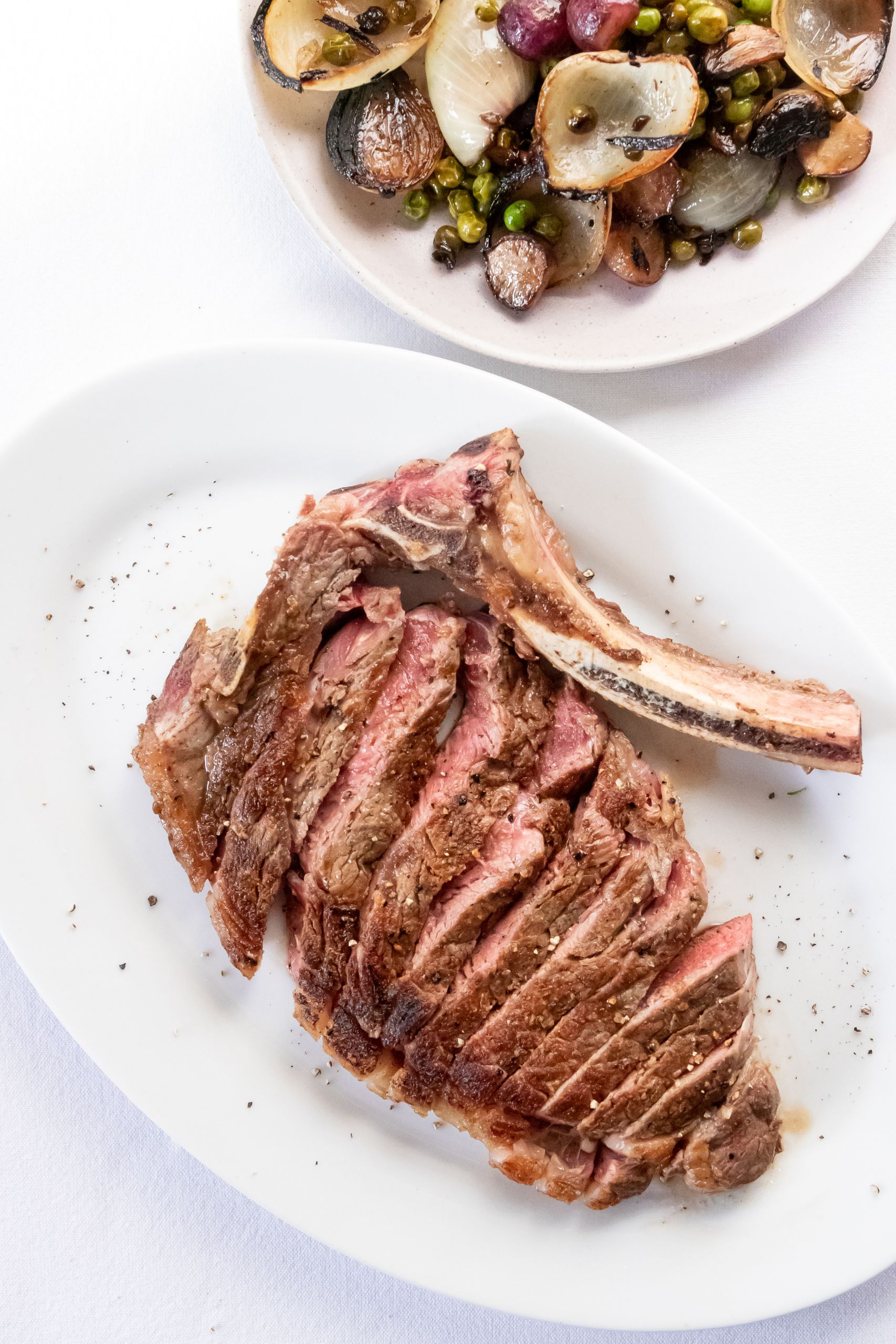 Top view composition of appetizing fresh ribeye steak cut on plate and served on table near mussel salad in fine restaurant