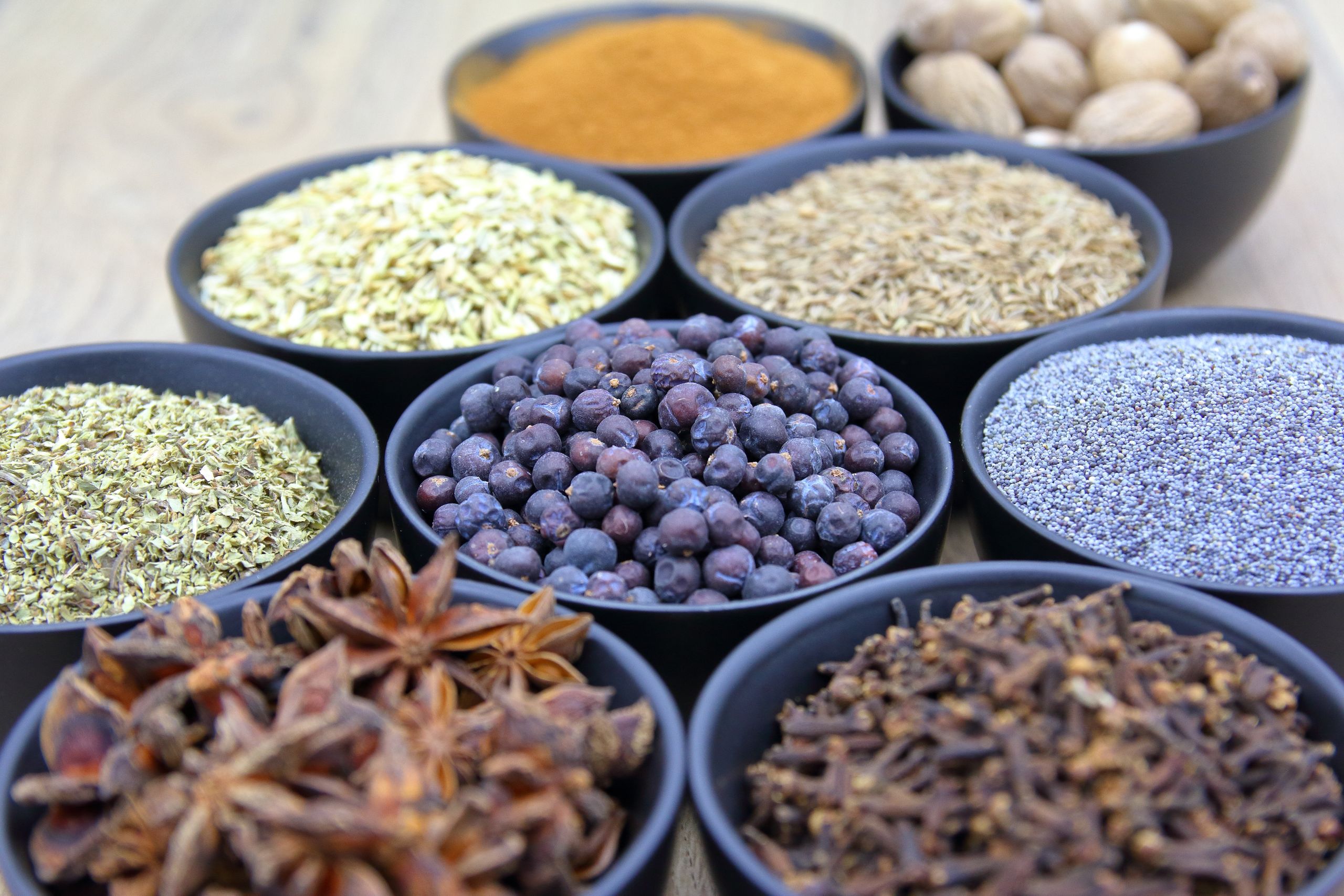 Top view of assorted spices in black bowls showcasing different colors and textures.