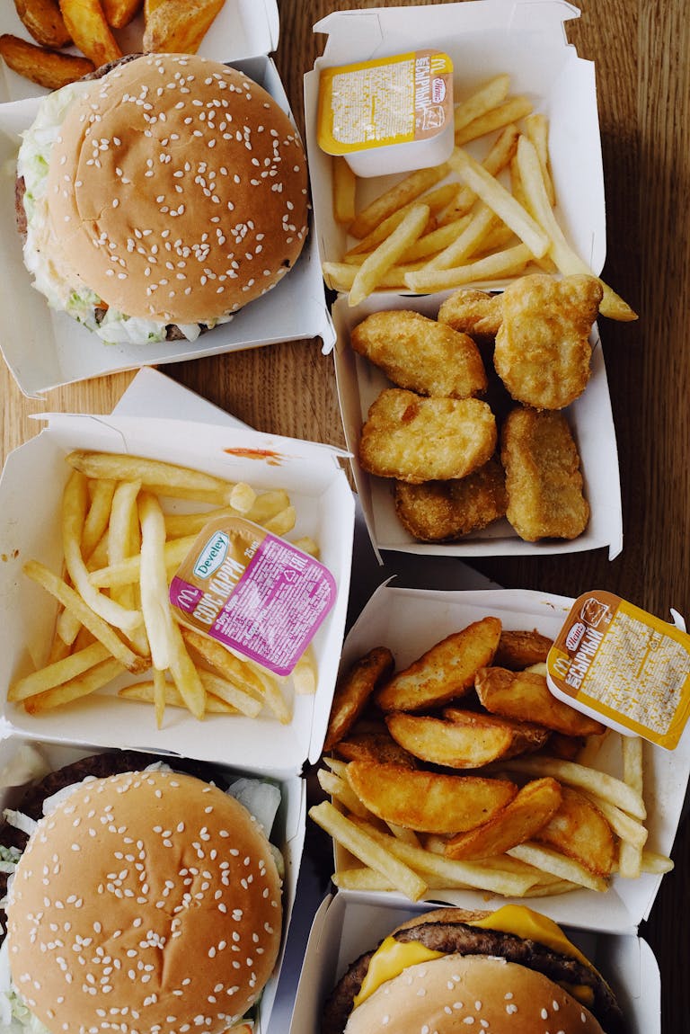 Top view of delicious junk food consisting of burgers and french fries placed on wooden table