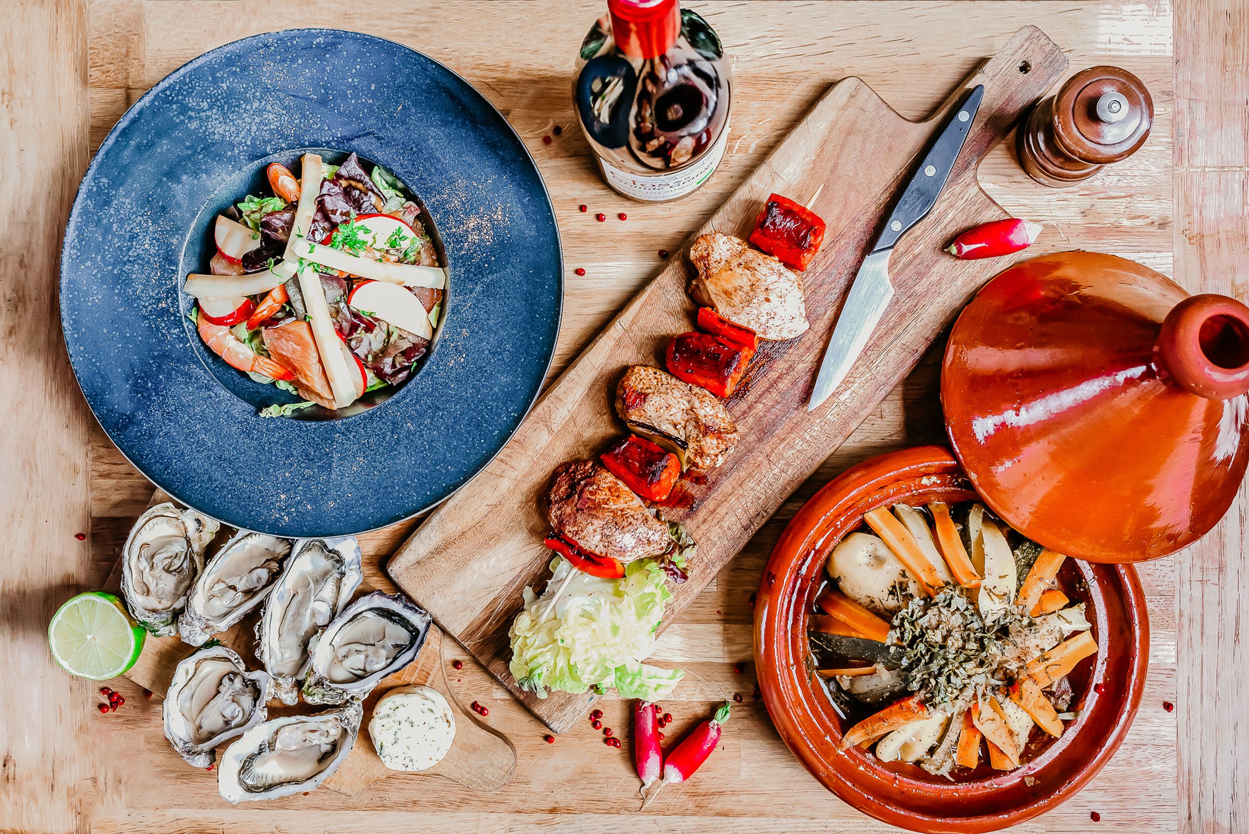 Top view of French gourmet dishes including seafood salad, grilled skewers, oysters, and wine in Angers, France.