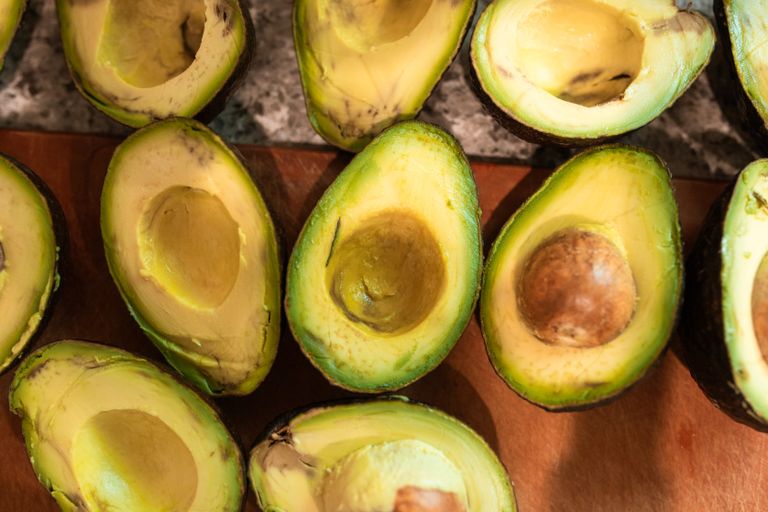 Top view of halved ripe avocados on a wooden surface, showcasing freshness and texture.