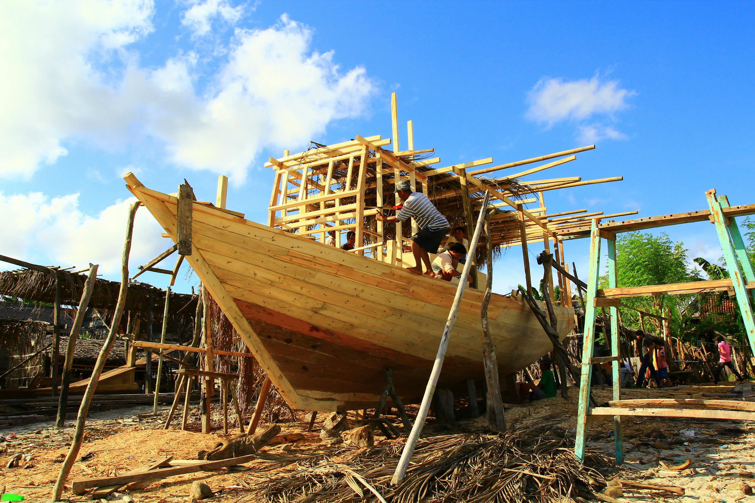 Traditional shipbuilding process on a sunny beach.