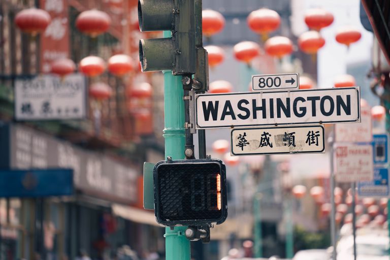 Traffic light and Washington street sign in bustling urban setting with lanterns.