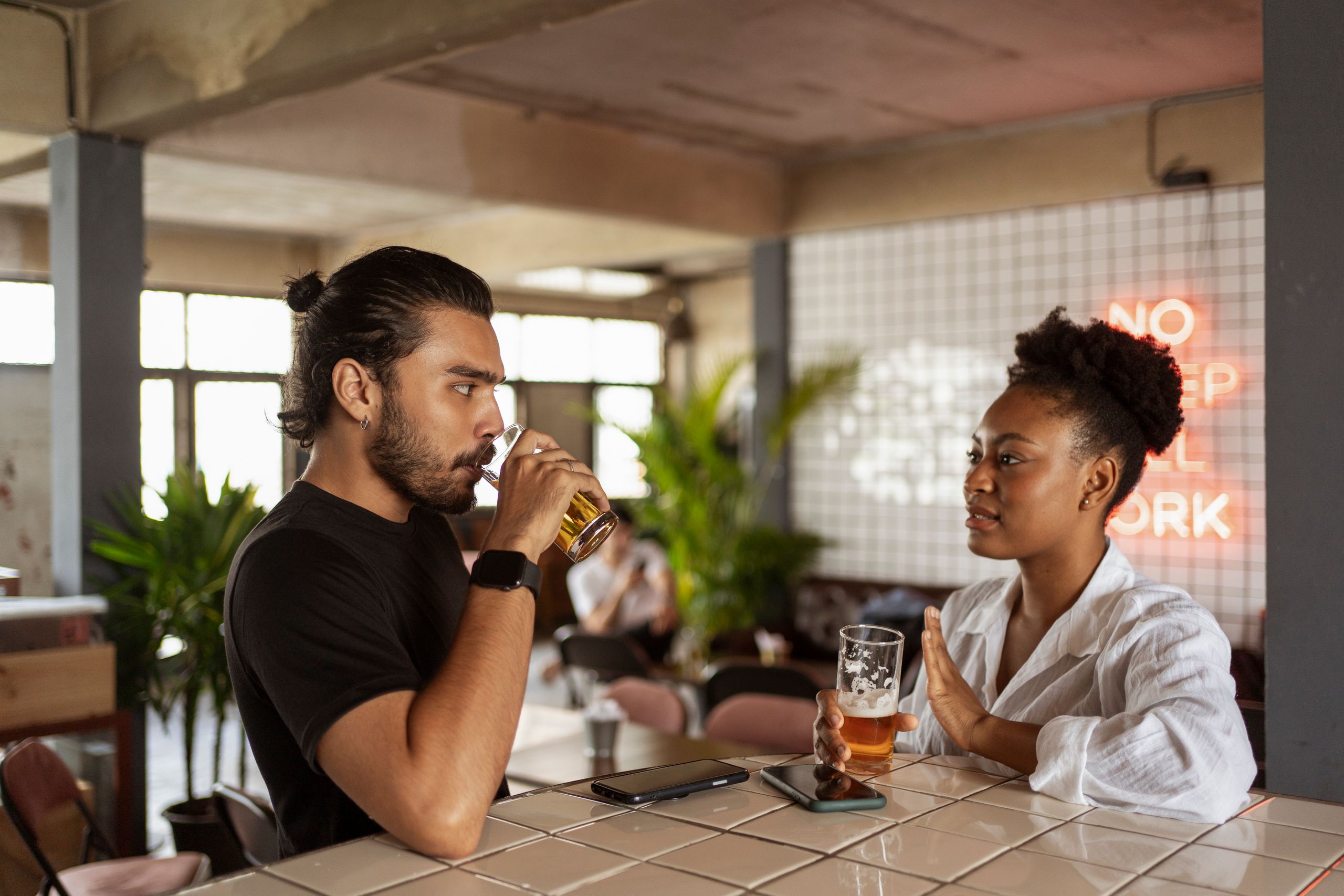 Two adults enjoying drinks and conversation in a contemporary cafe environment.