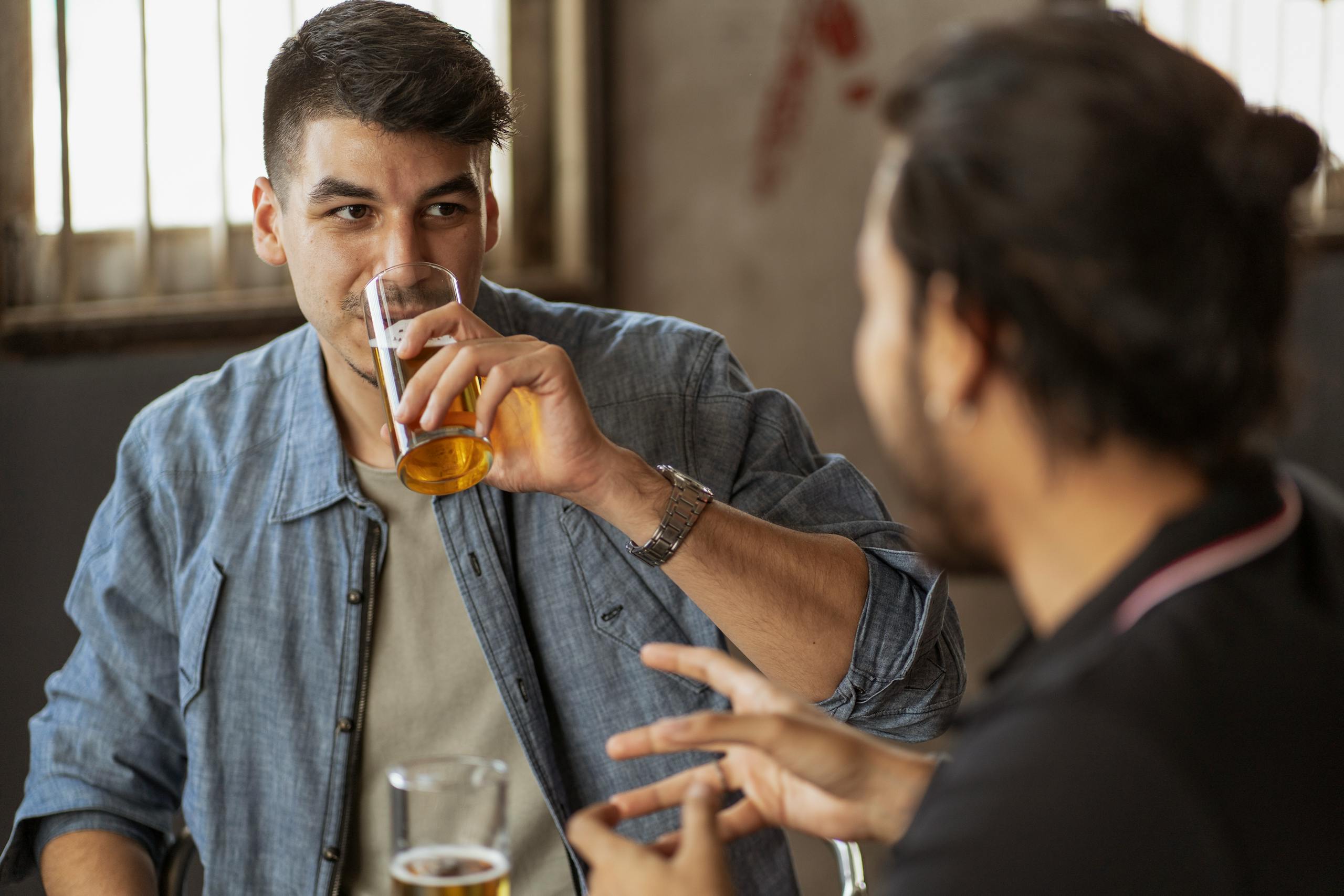 Two friends enjoying a casual conversation over drinks indoors. Perfect for lifestyle and social themes.