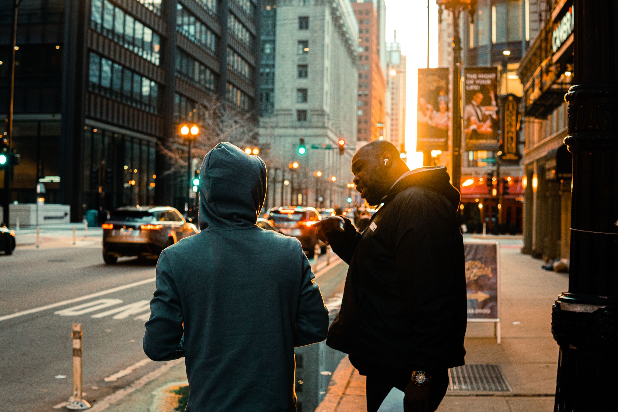 Two men converse on a bustling street in downtown Chicago at sunrise, capturing urban life.