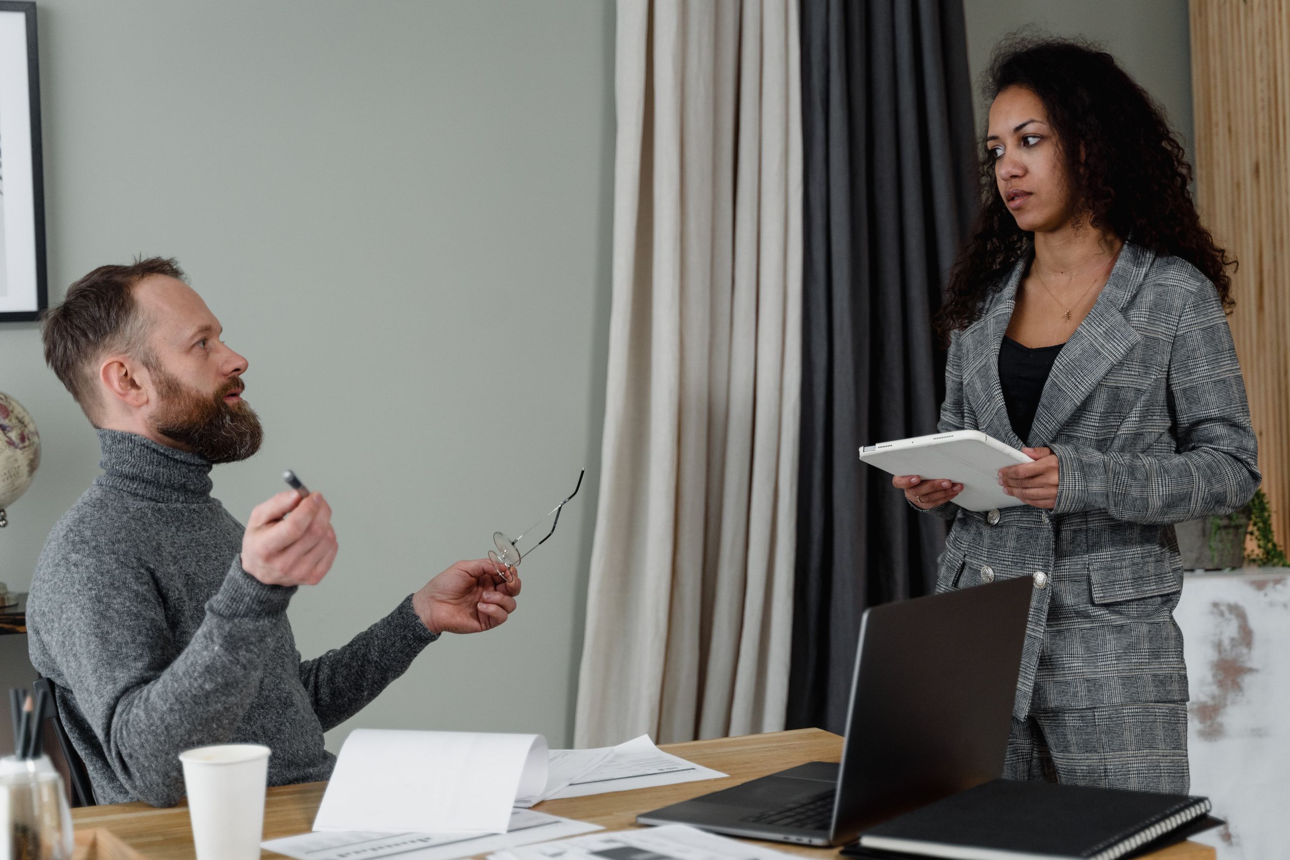 Two professionals discussing work tasks at a modern office desk.