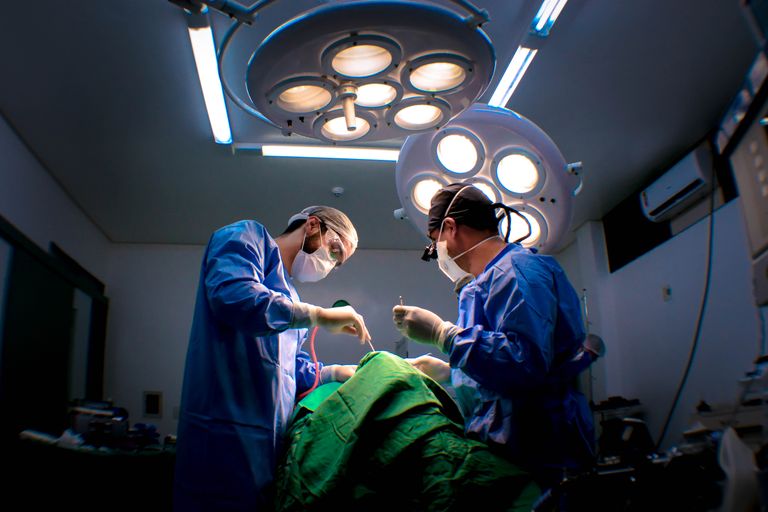 Two surgeons performing surgery in a well-equipped operating room.