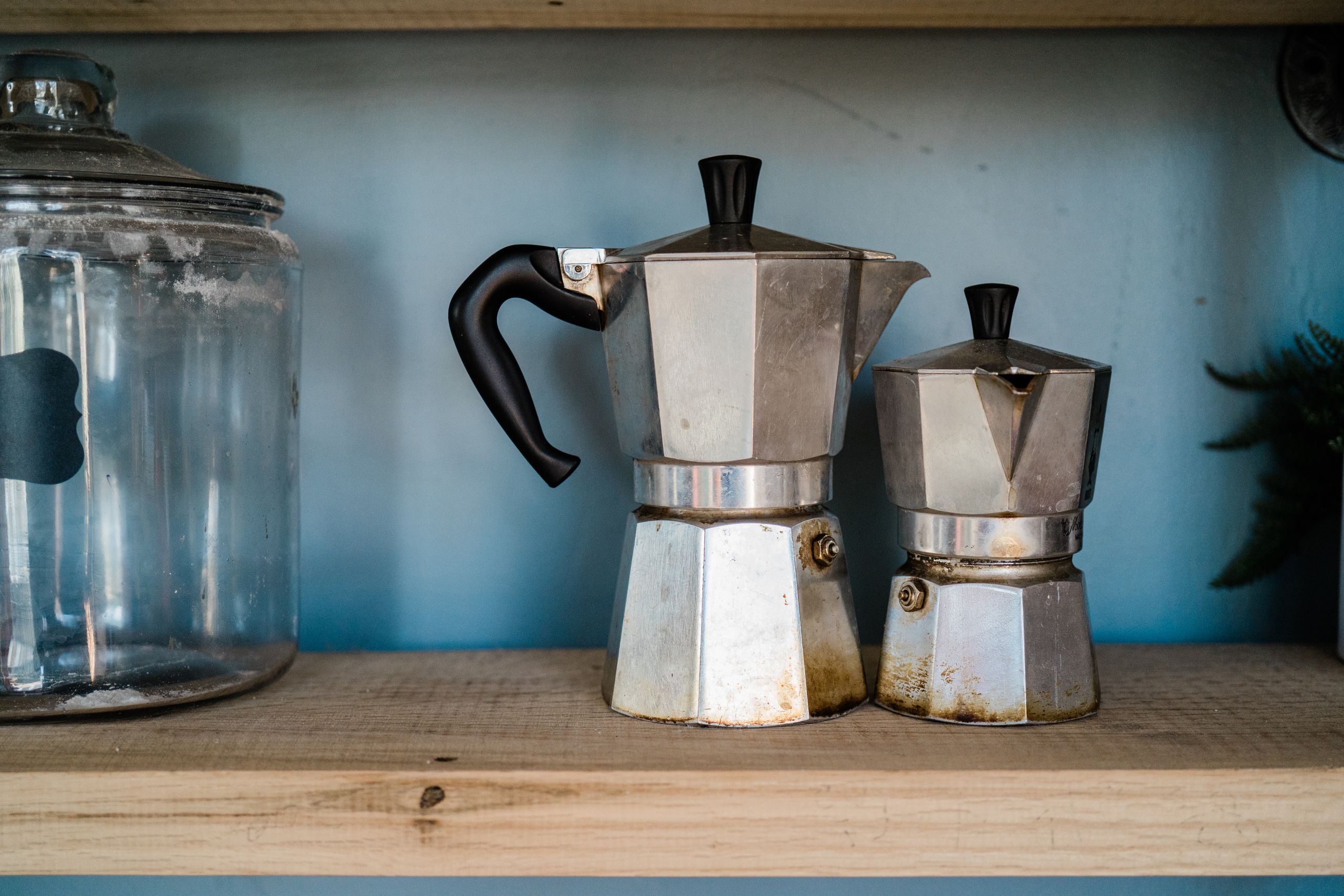 Two vintage aluminum coffee pots displayed on a wooden kitchen shelf, showcasing classic design.