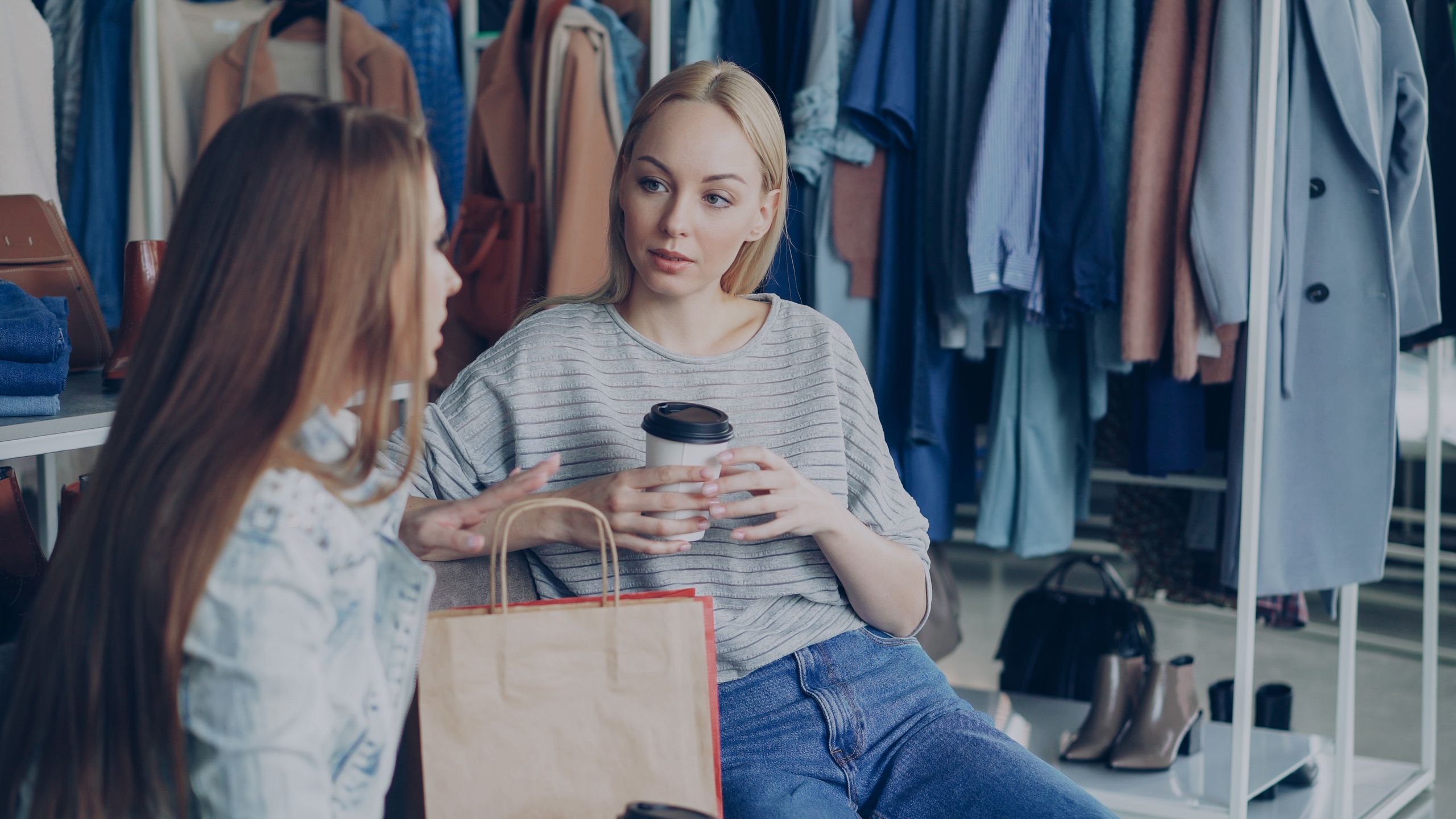 Two women enjoying a conversation during a shopping trip at a clothing boutique.