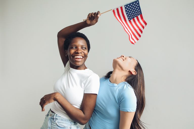 Two women joyfully celebrating with an American flag on Independence Day.