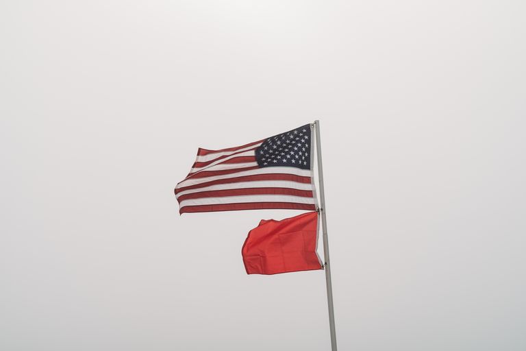 United States and warning flags on display against an overcast sky at Orange Beach, AL.
