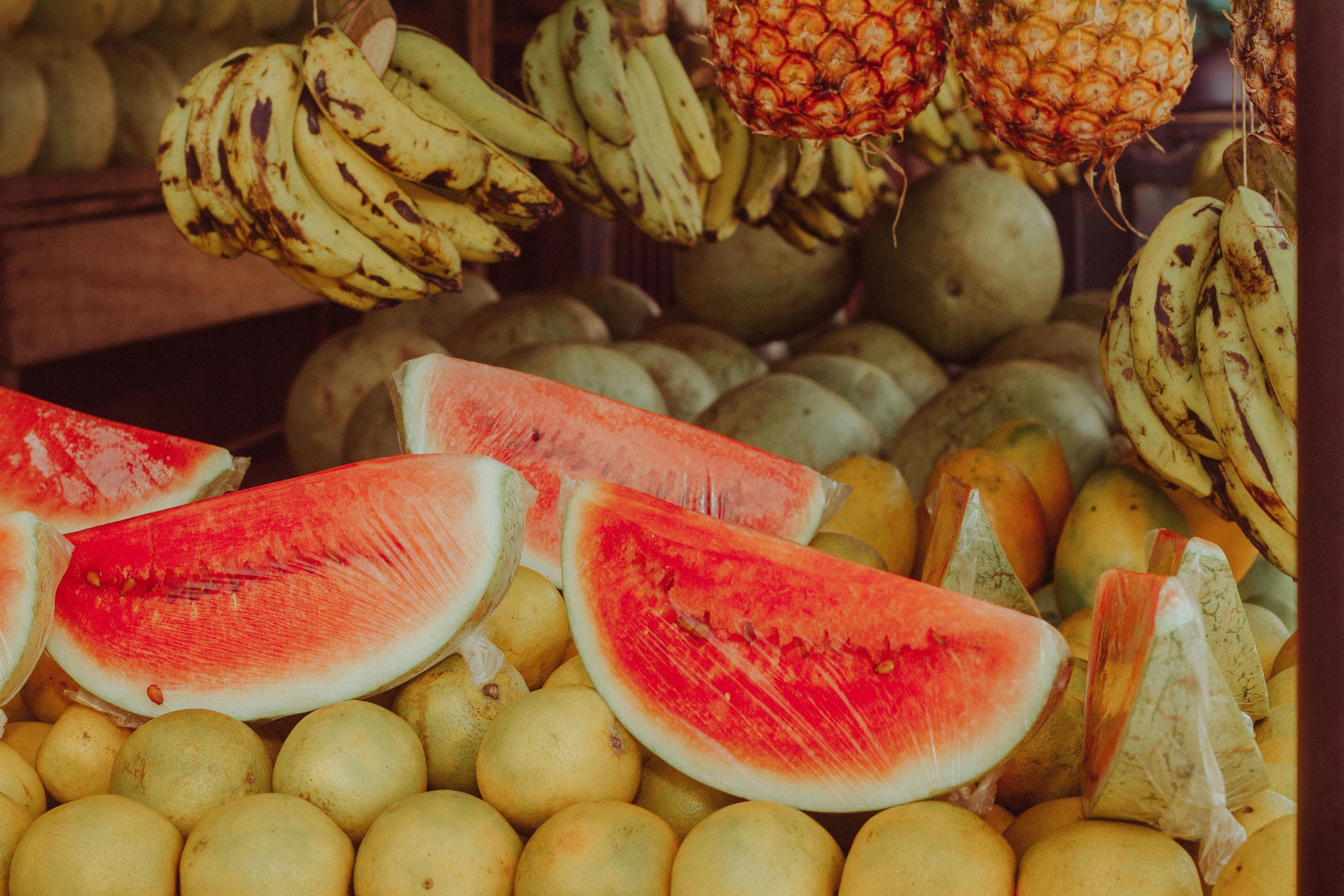 Vibrant display of bananas, watermelon, and pineapples at a market in Nigeria.