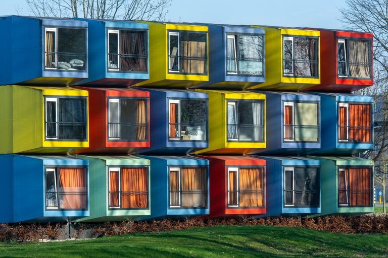 Vibrant exterior of colorful modular housing units with varied window designs.