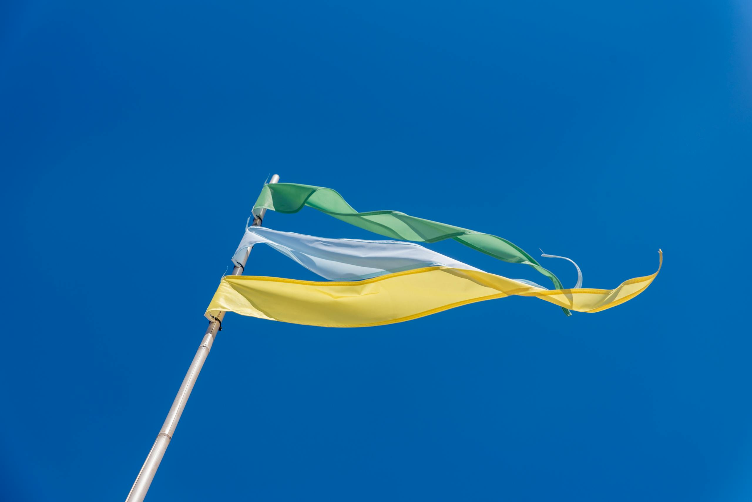 Vibrant green, white, and yellow flags waving in the clear blue sky.