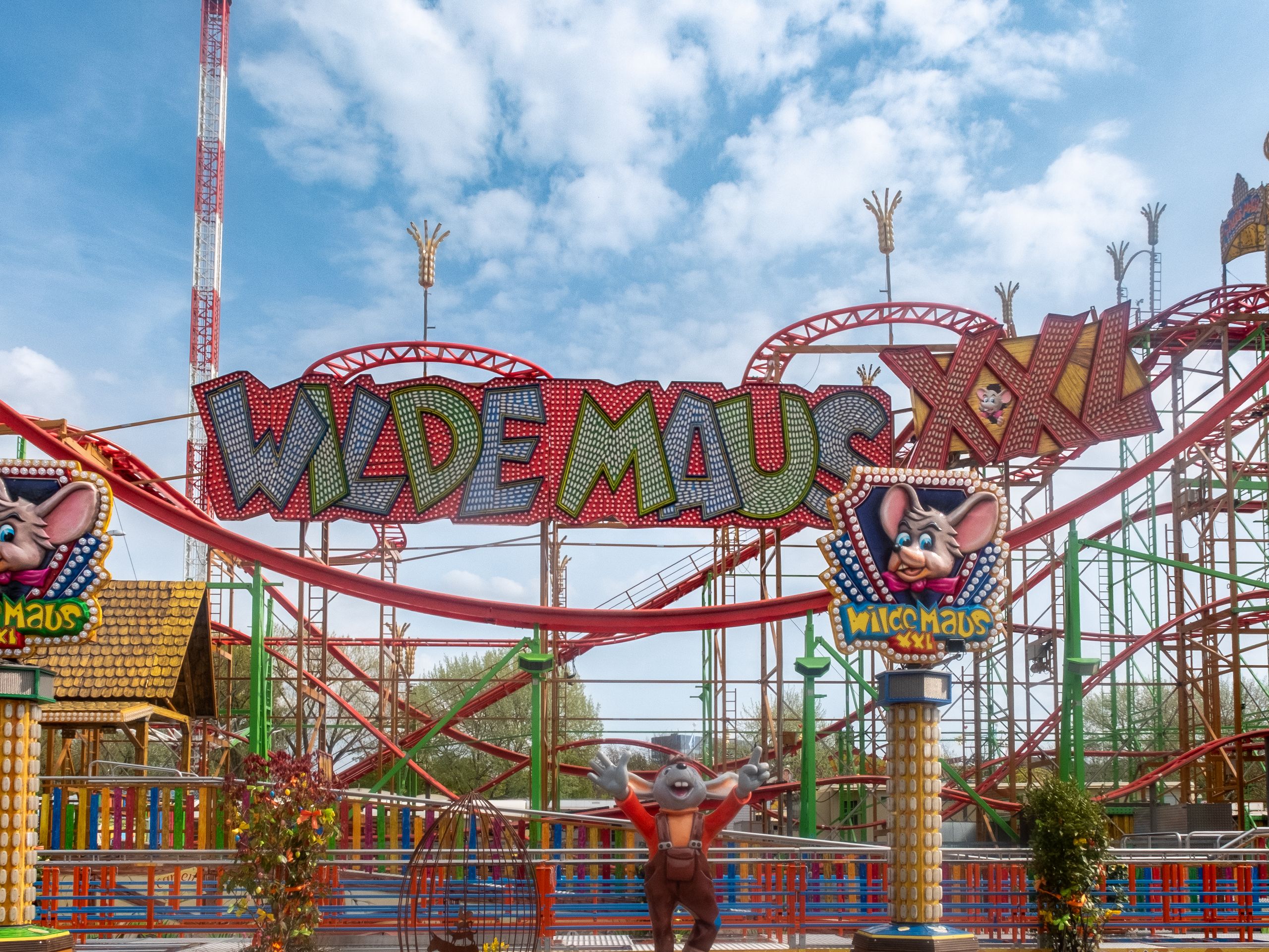Vibrant image of Wilde Maus XXL roller coaster ride under blue sky in Hamburg, Germany.