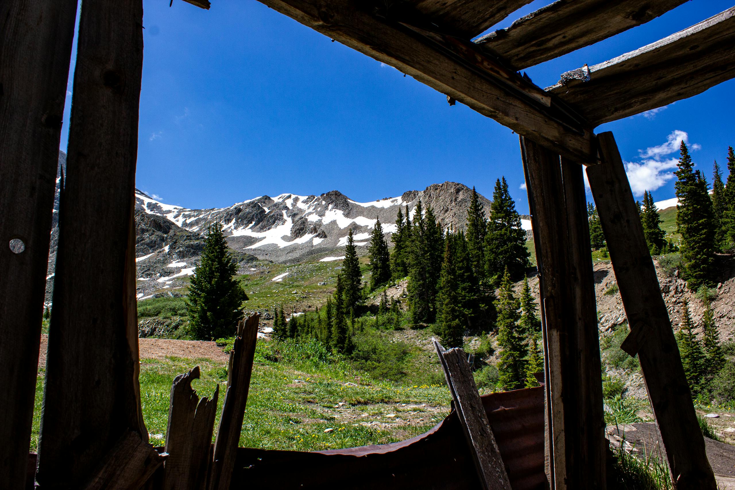 View of snow-capped mountains from an abandoned cabin in Frisco, Colorado.