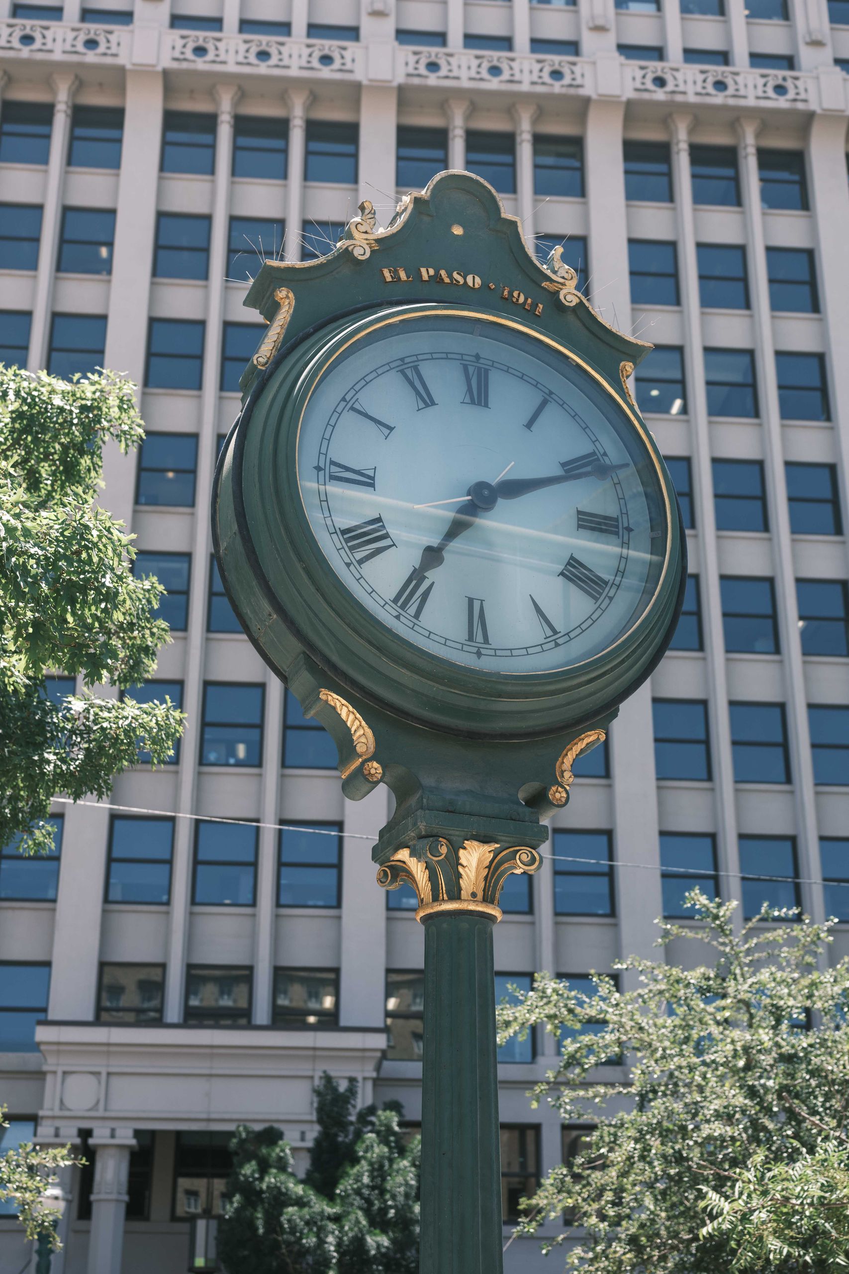 Vintage street clock against an urban backdrop in El Paso, showcasing classic architecture.