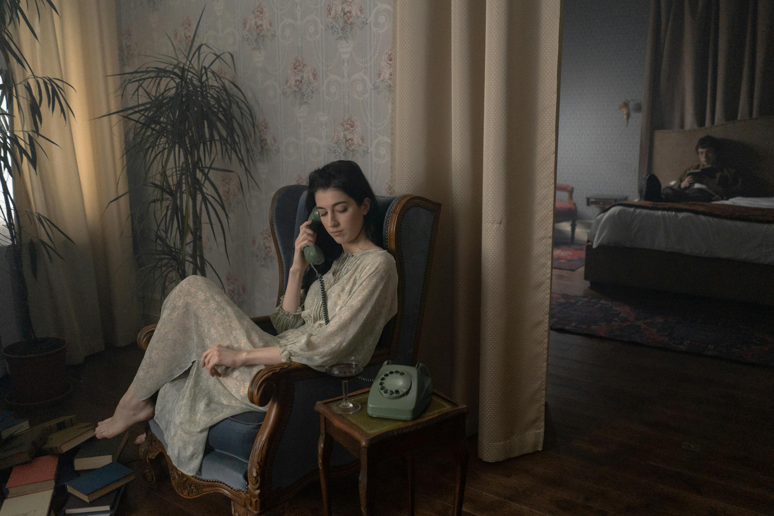 Vintage-themed indoor setting with a woman talking on a retro phone, surrounded by plants.