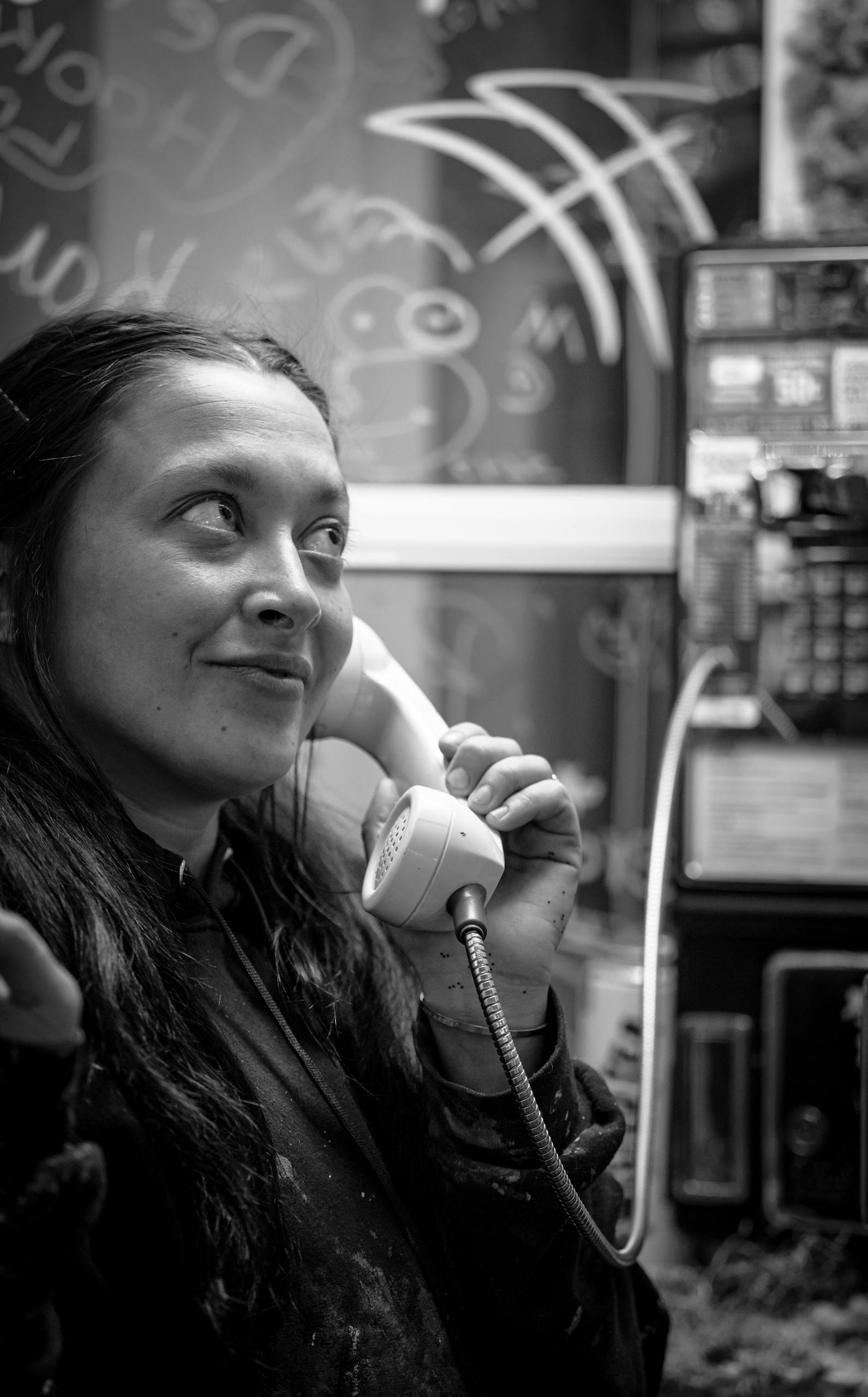 Woman engages in call with payphone, monochrome image adds a classic touch.