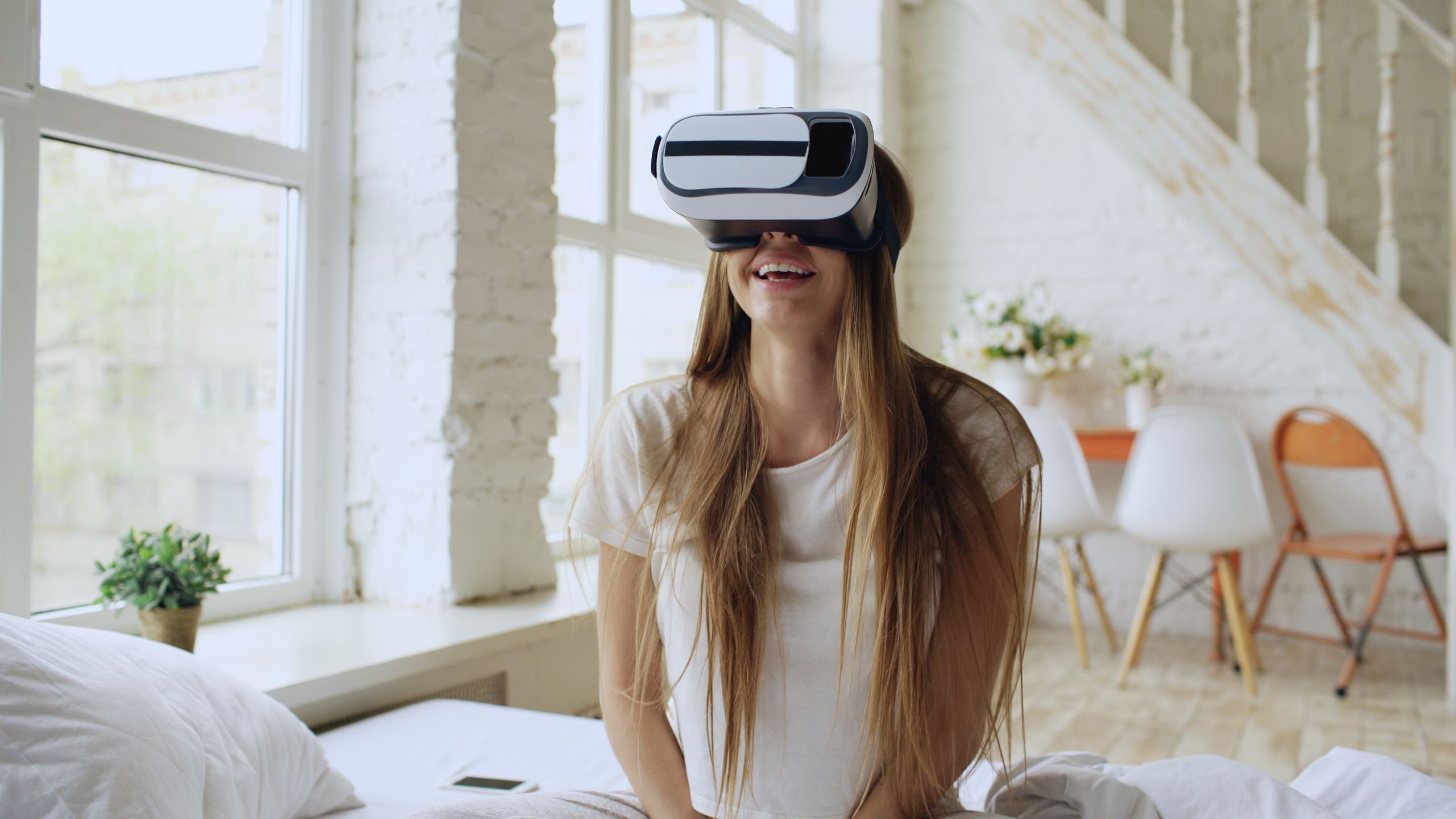 Woman enjoying virtual reality experience at home, smiling and relaxed.