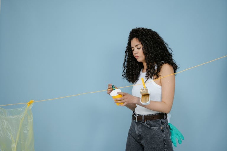 Woman with curly hair holds drink in studio promoting zero waste lifestyle.