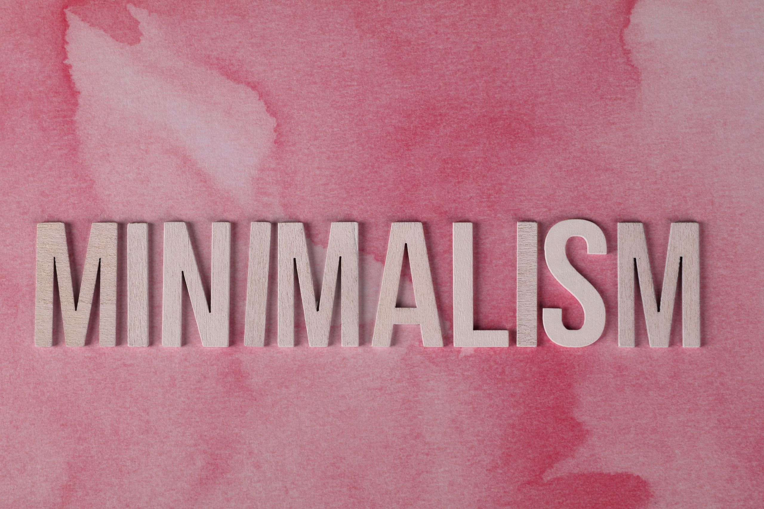 Wooden letters spelling 'MINIMALISM' on a pink textured background depicting a minimalist style.