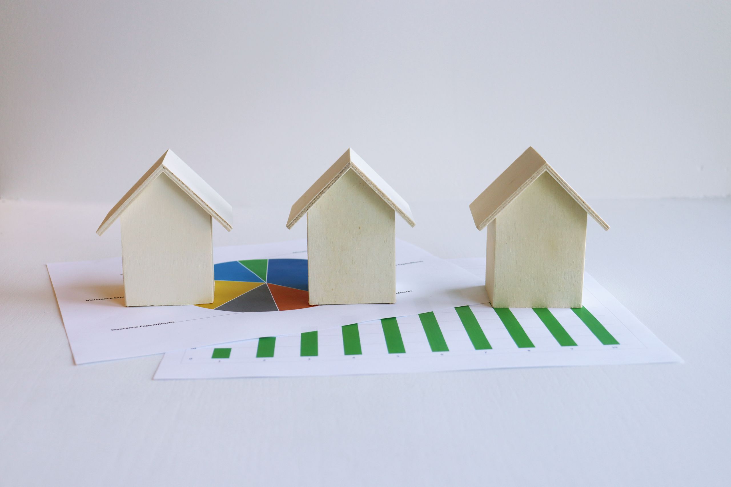 Wooden model houses on graphs depict real estate market analysis and trends.