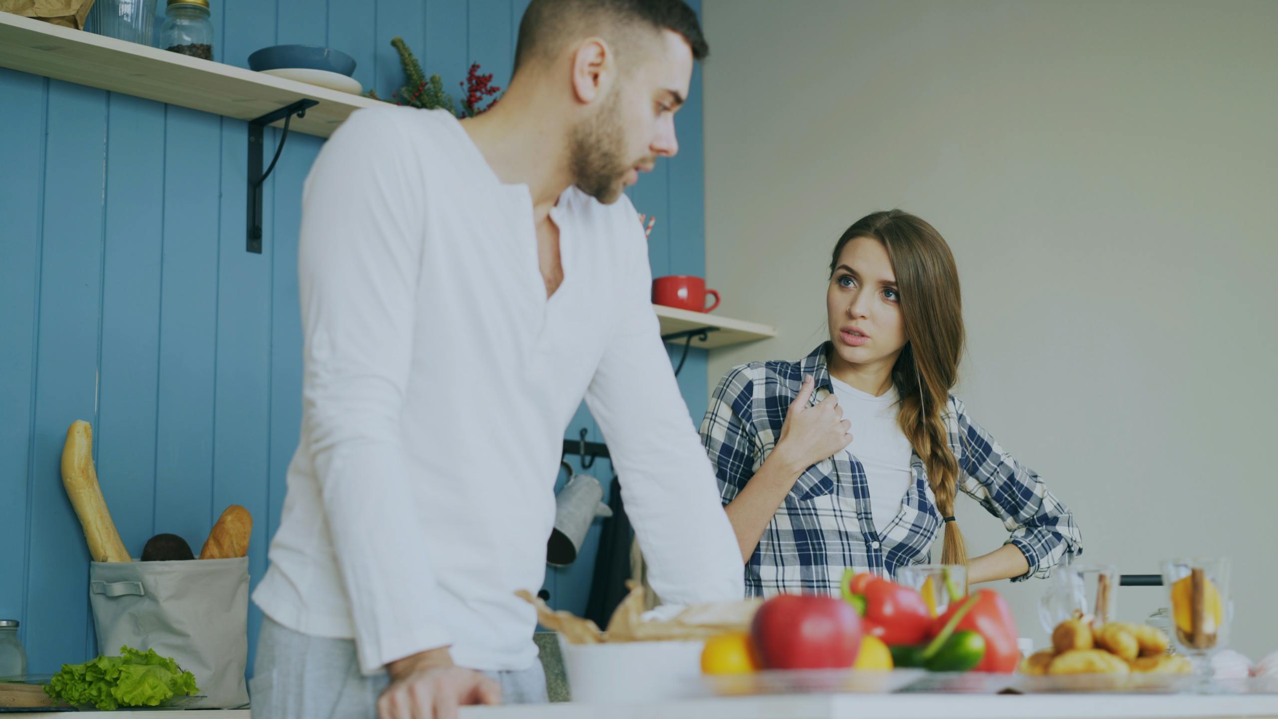 Young couple engaged in a conversation in a stylish kitchen with fresh fruits.