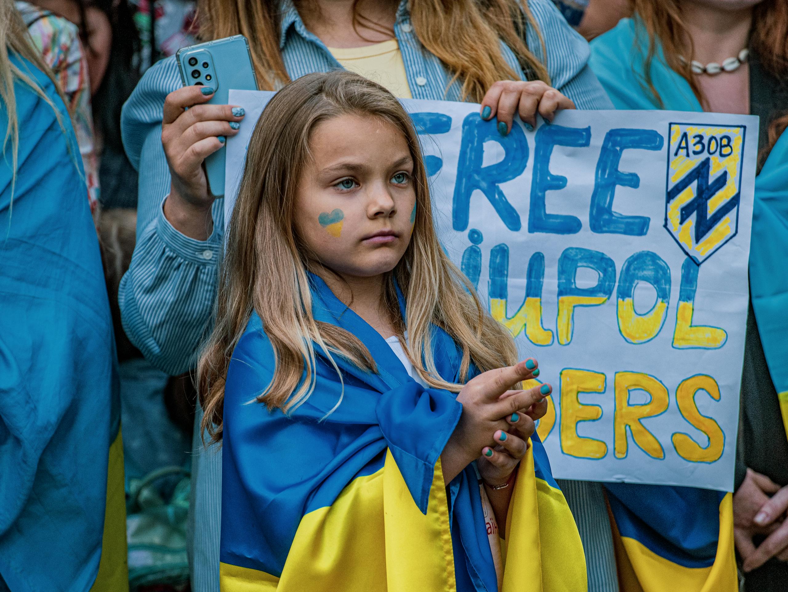Young girl at a peaceful rally supporting Ukraine, holding a protest sign.