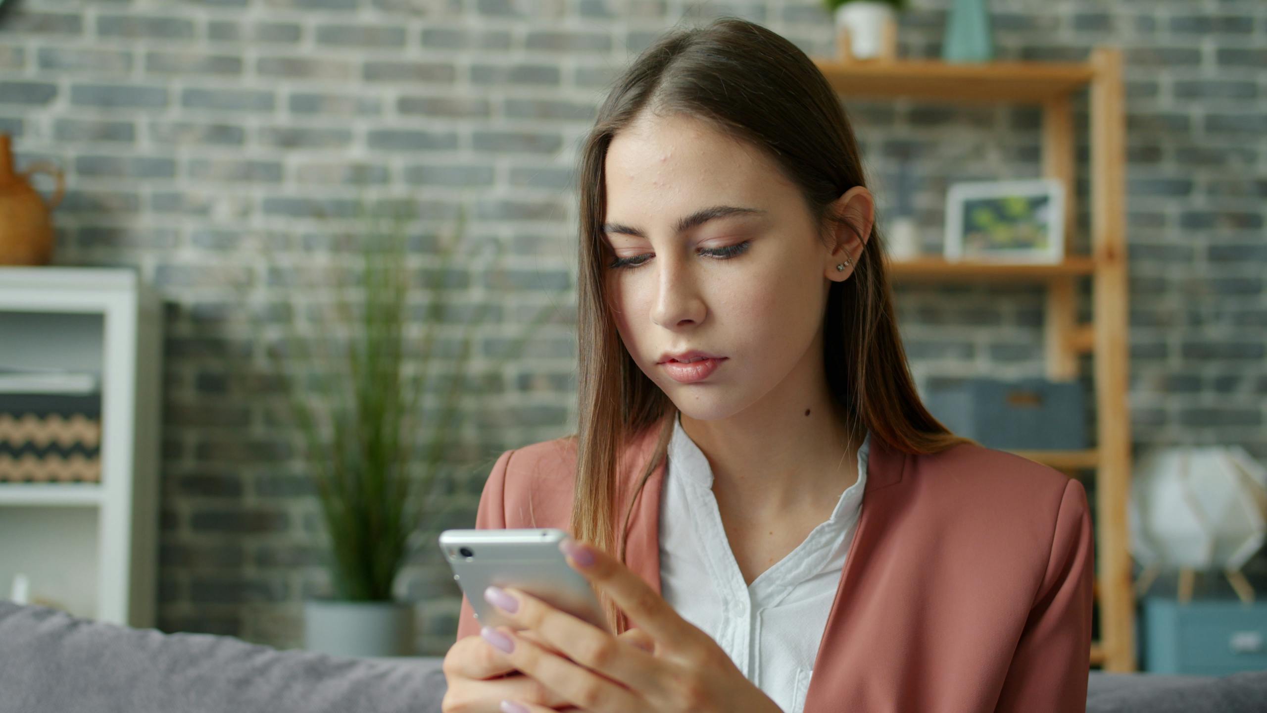 Young woman focused on smartphone in stylish, cozy living room.