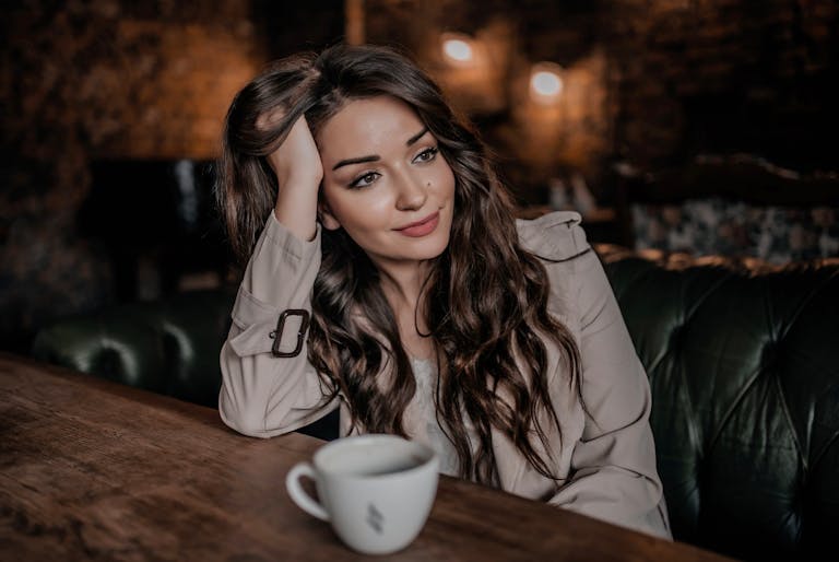 Young woman with long hair enjoys a tranquil moment in a cozy café with a cup of coffee.