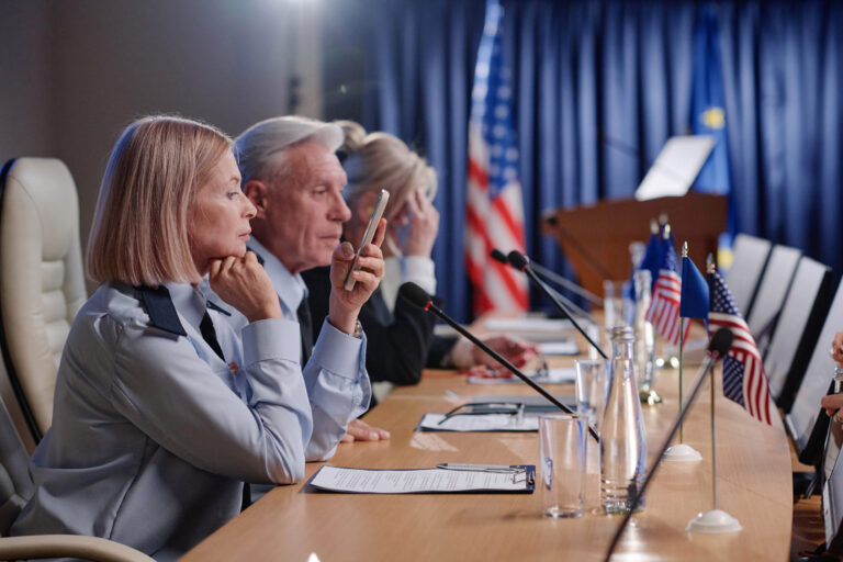 Group of people sitting at table with microphones and performing during international conference