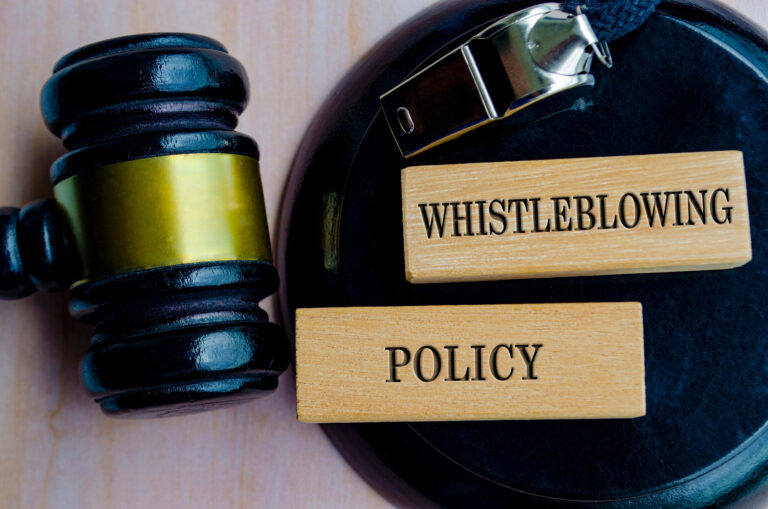 Whistleblower Policy text engraved on wooden blocks with lawyer gavel background