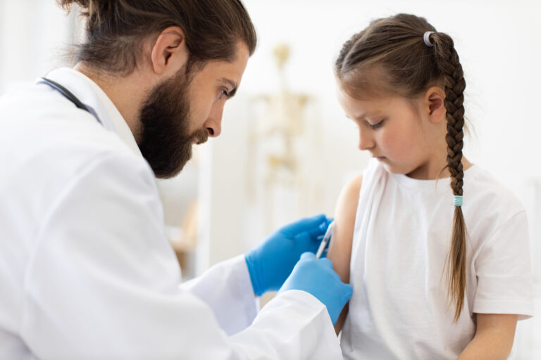 Doctor administering vaccine to young girl in medical clinic