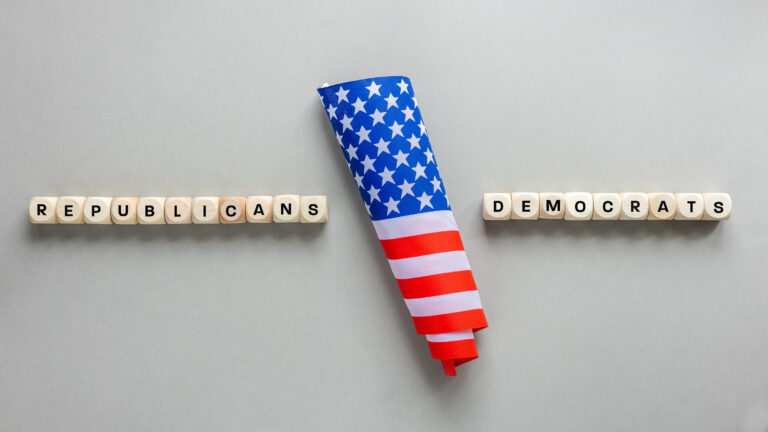 Republicans vs Democrats. Conceptual words written on wooden blocks. American flag and on the sides Republicans and Democrats. Cracked gray background, copy space, flat lay