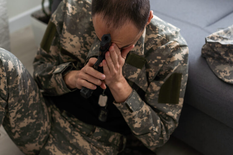 sad soldier has psychological problems holding his head in a squatting position
