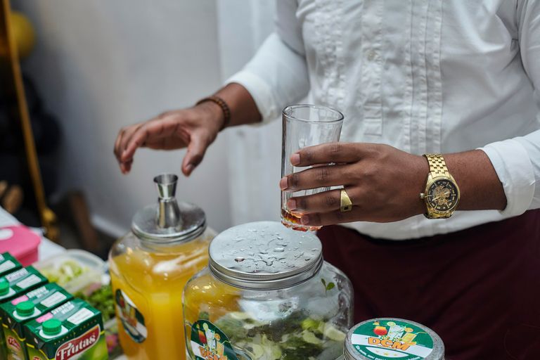 A bartender mixes drinks with fresh ingredients and juice indoors, showcasing beverage preparation.