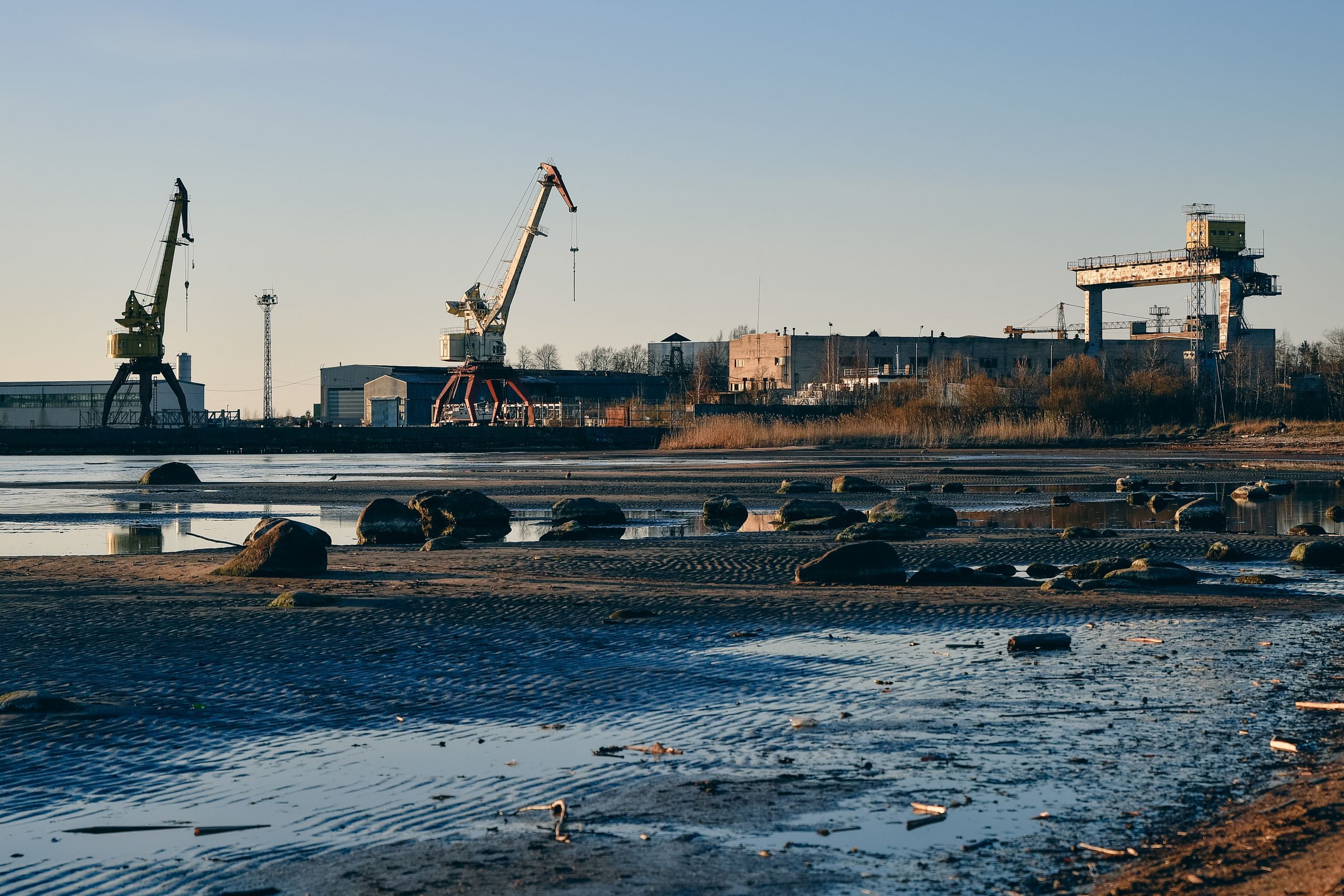 A serene view of Loksa shipyard in Estonia with cranes and calm waters at sunset.