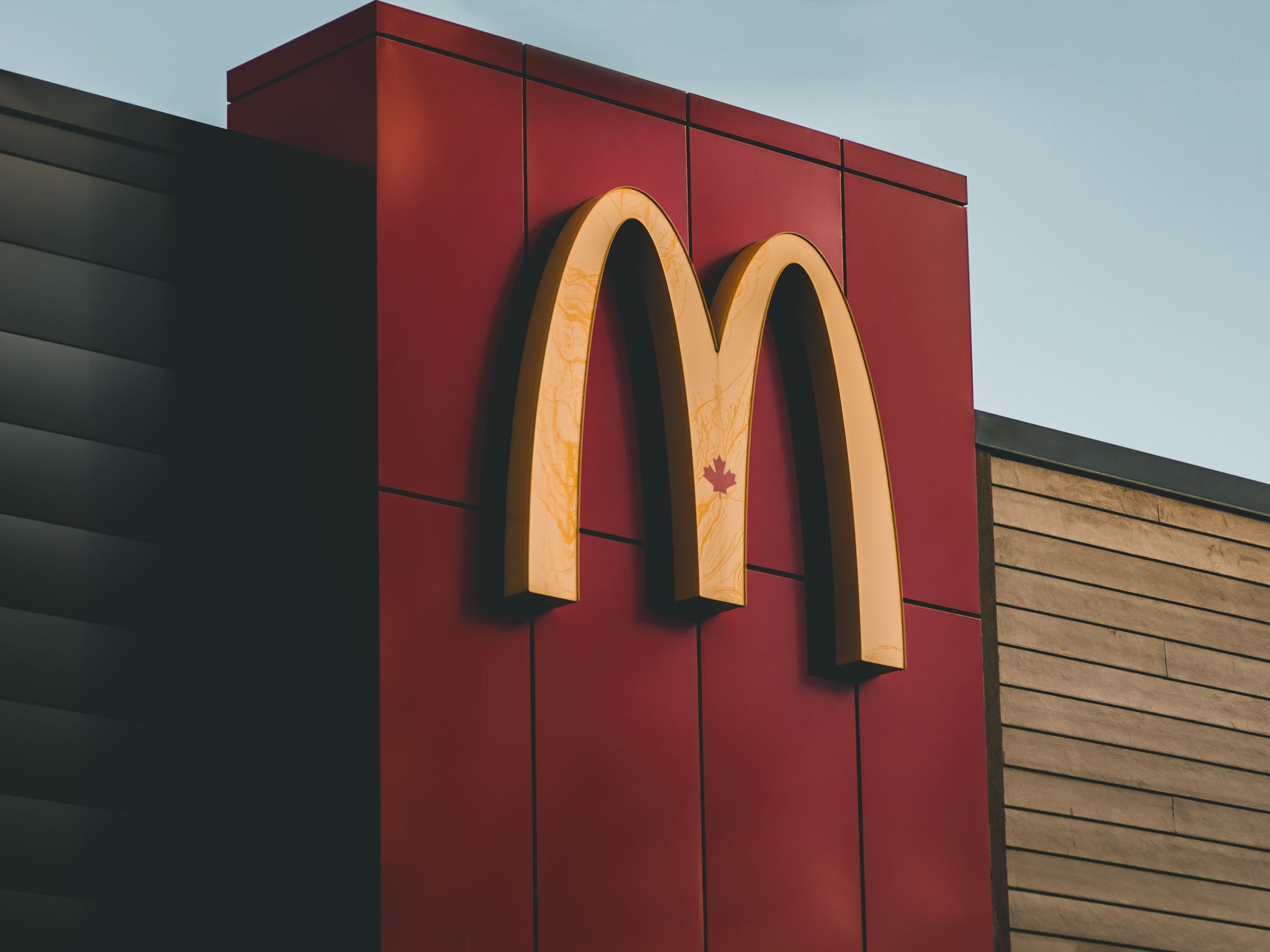 Close-up of McDonald's logo featuring a maple leaf on a building in Surrey, BC, Canada.