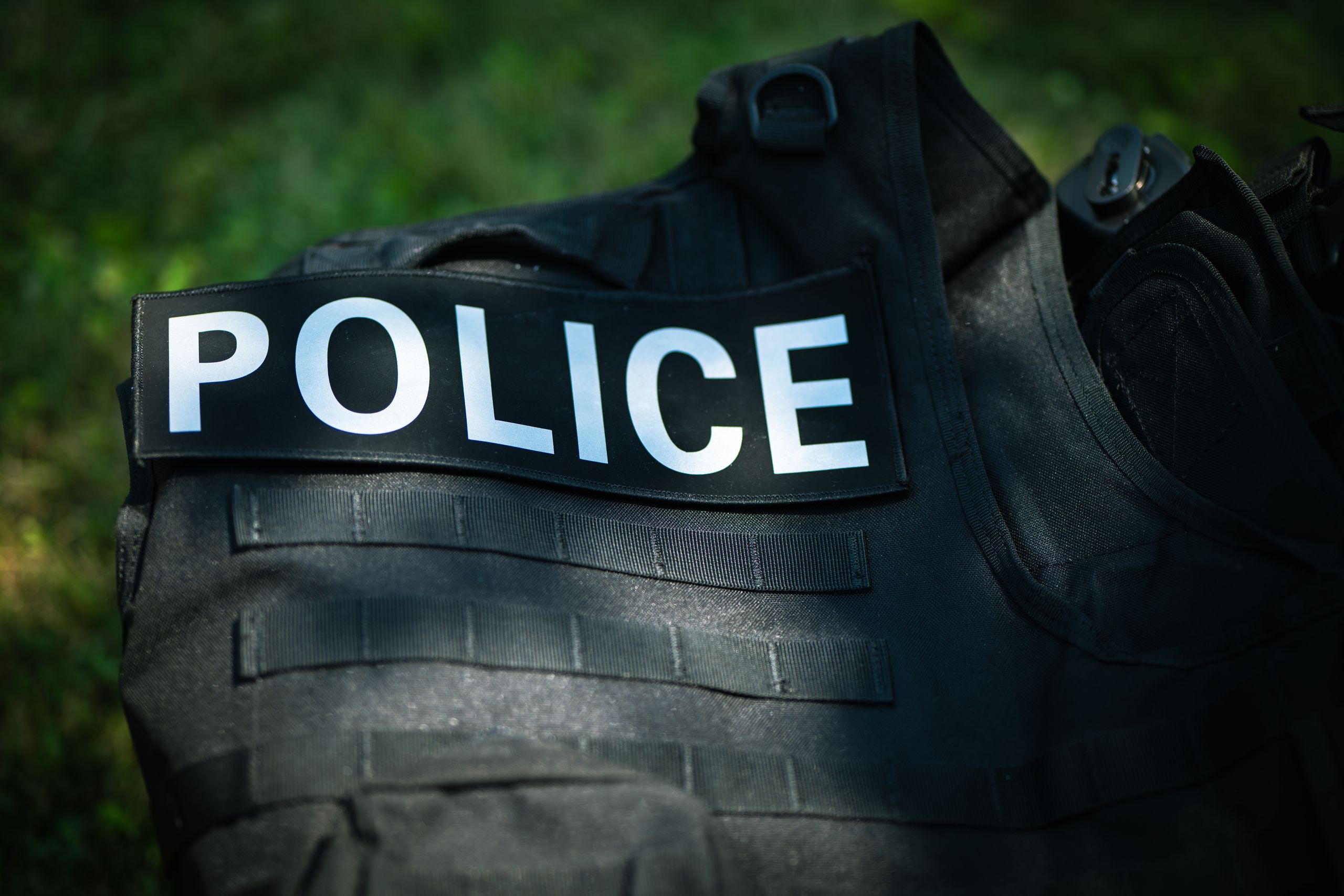 Detailed shot of a police vest lying outdoors, highlighting law enforcement gear.