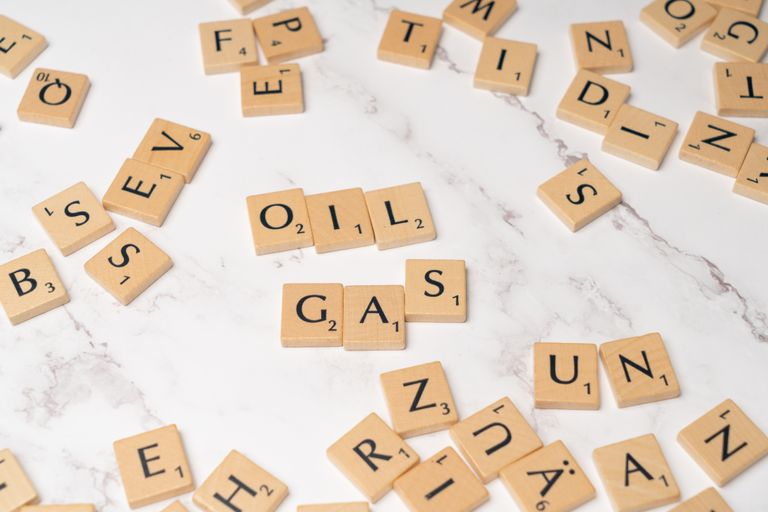 Scrabble tiles on marble spelling 'oil' and 'gas', concept for energy and creativity.