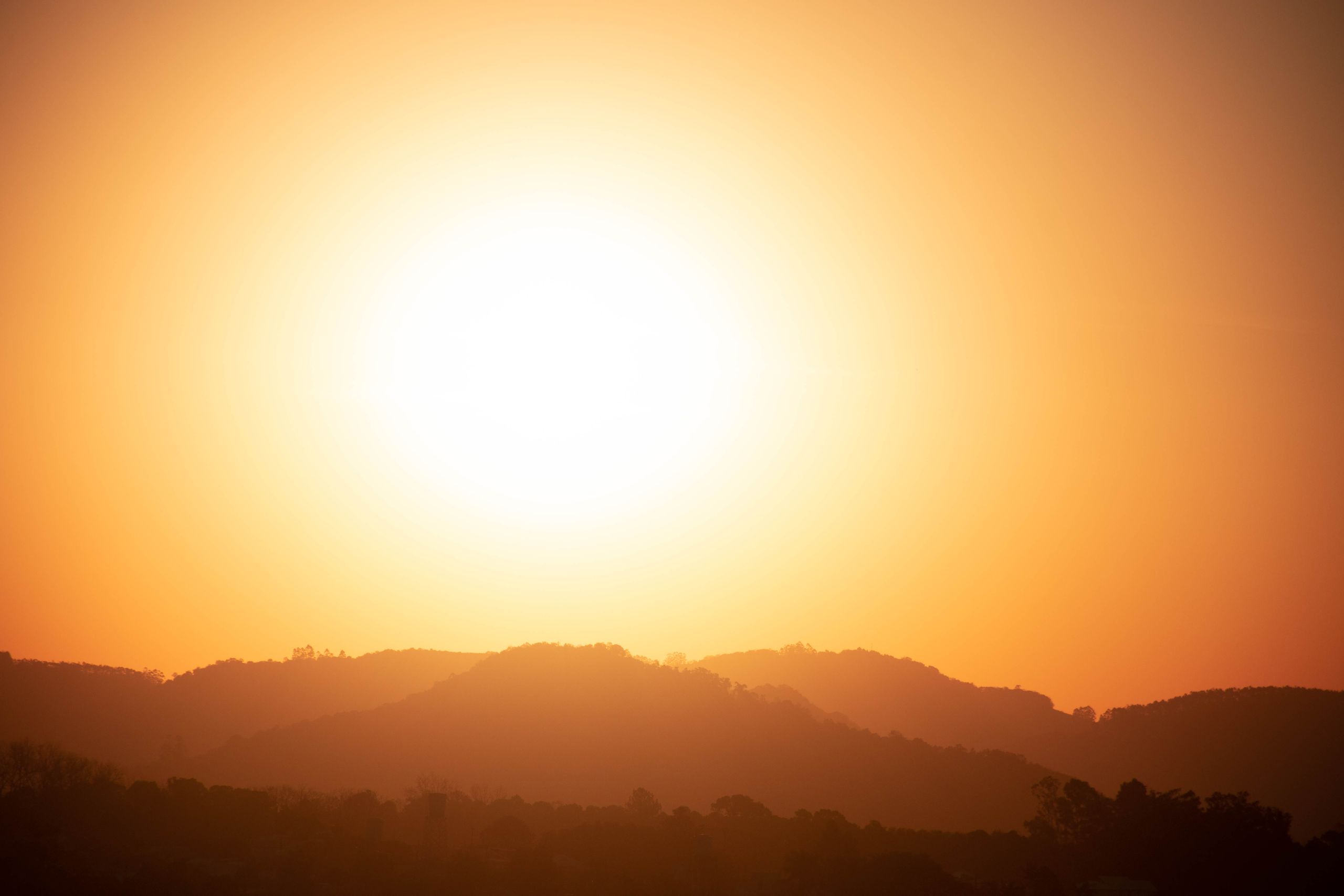 Silhouette of mountains under a bright sunset with a golden sky.