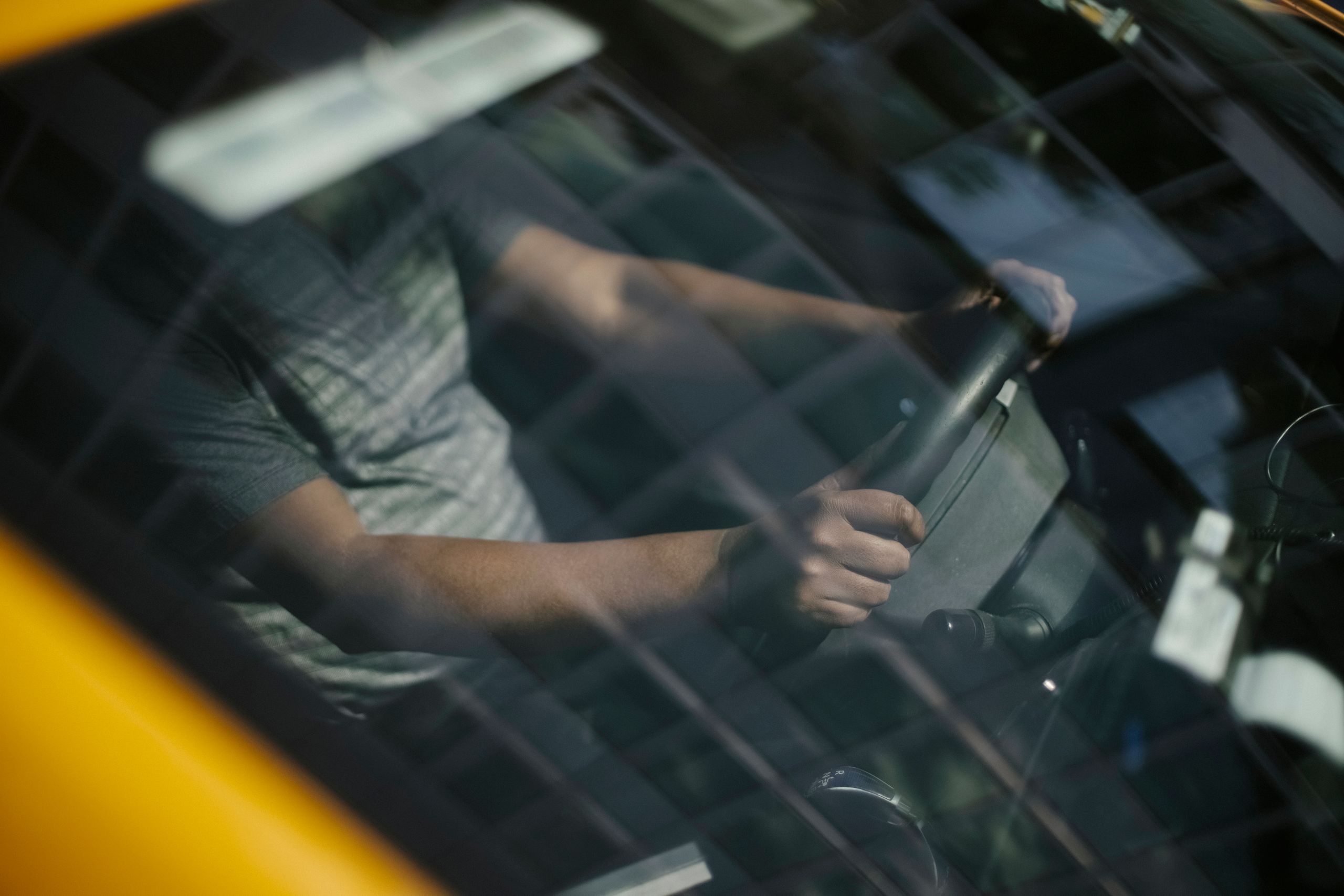Through glass of windshield of ethnic crop male driver in cab while working in city