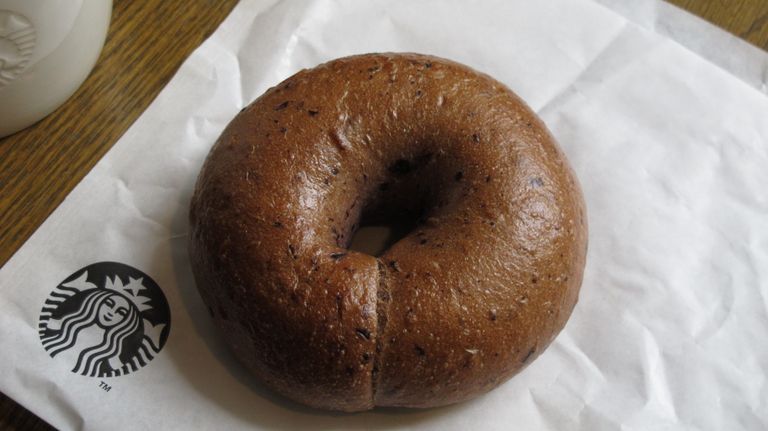 Top view of a fresh blueberry bagel resting on Starbucks paper, perfect for breakfast visuals.