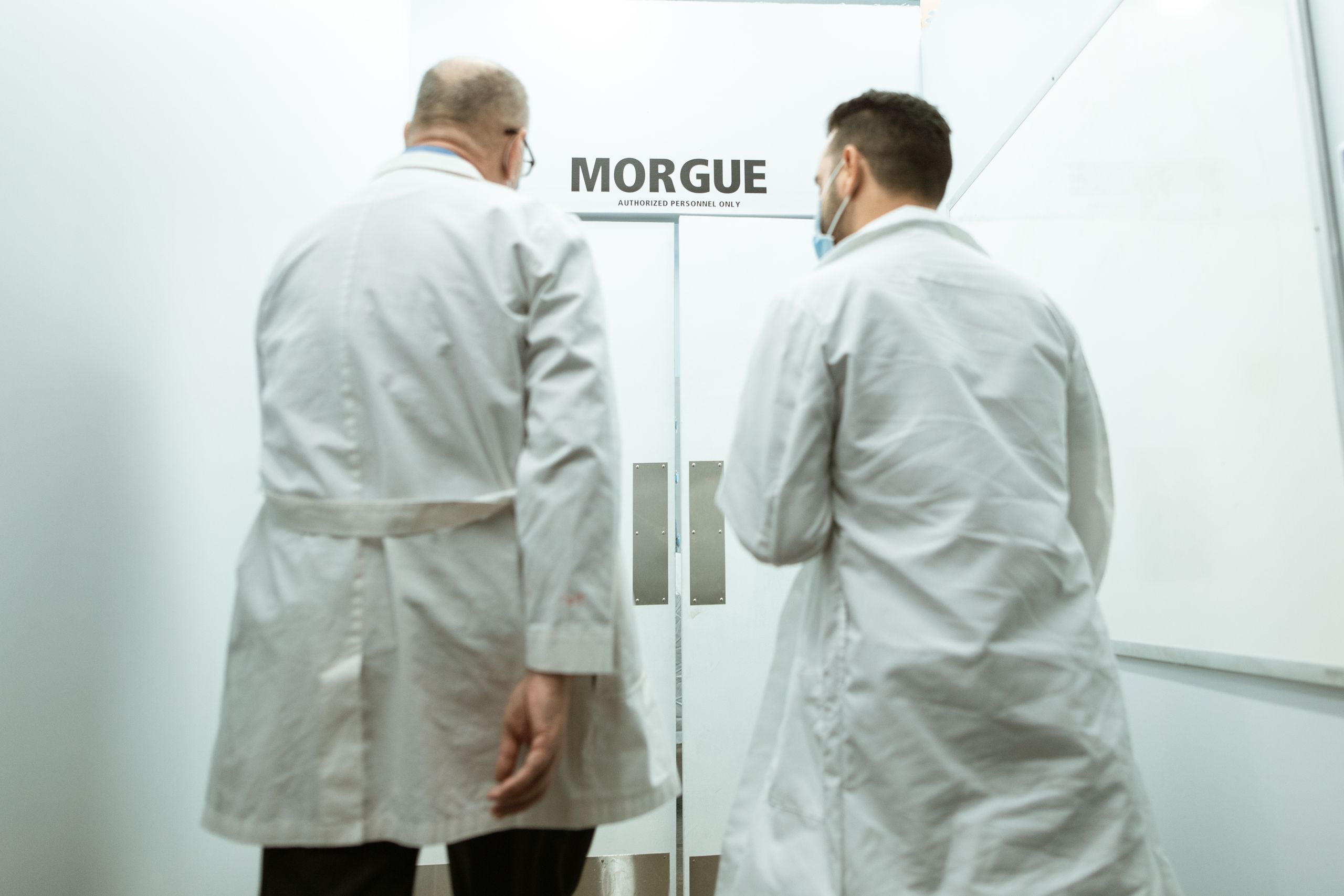 Two doctors entering a morgue, emphasizing a clinical and somber atmosphere.
