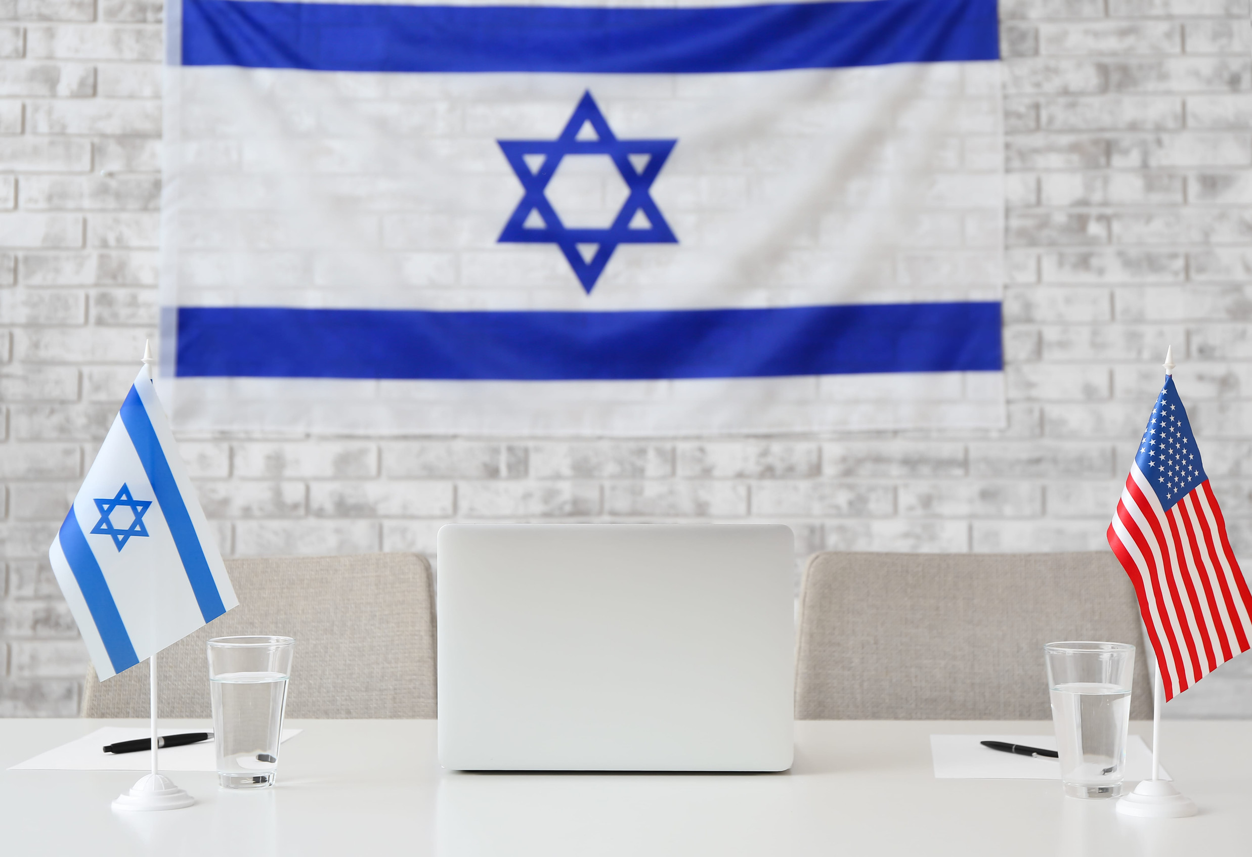 Flags of Israel and USA on table in embassy office