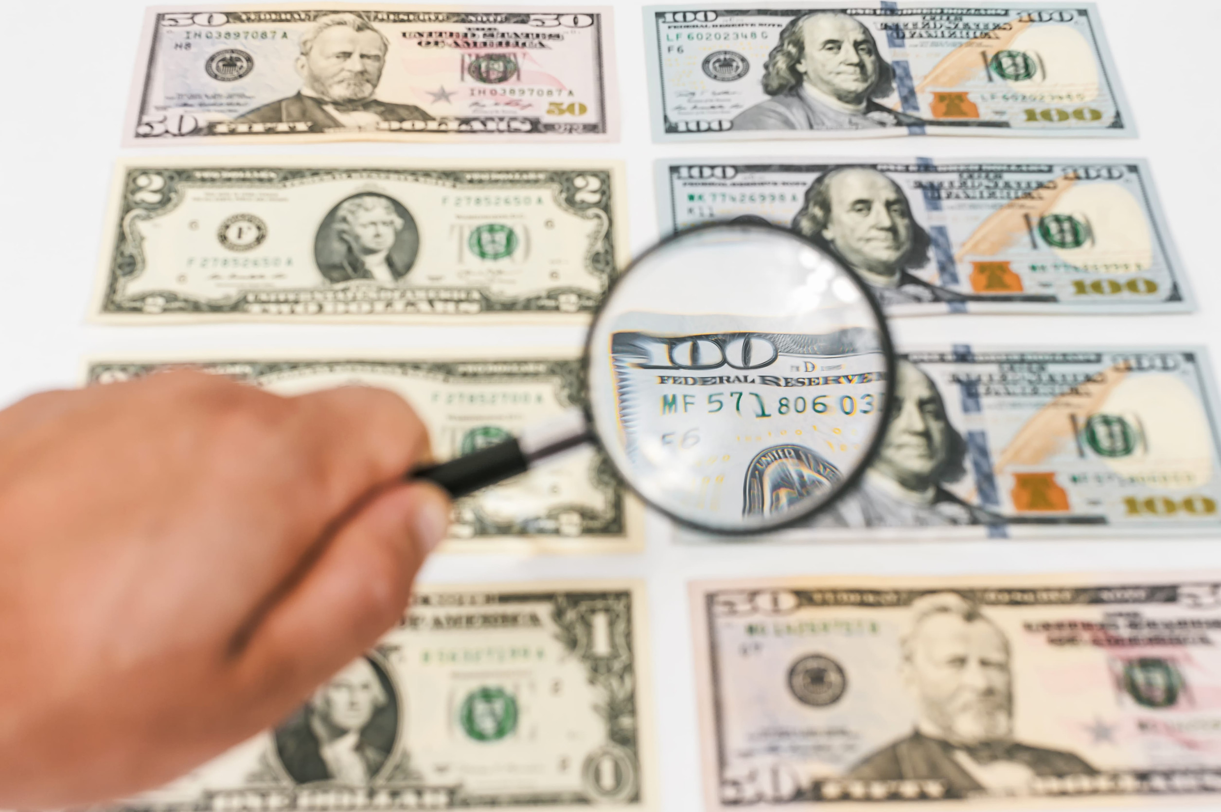 Magnifying glass in the hands of a man on the background of dollars
