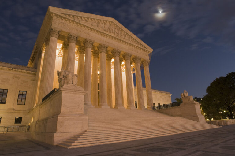 A night shot of the front of the US Supreme Court in Washington, DC.